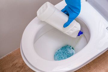 Clean toilet with cleaning agent bleaching gel and hand in