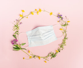Protective medical mask and fresh flowers on a pink background. Flat layout place for text your design concept health