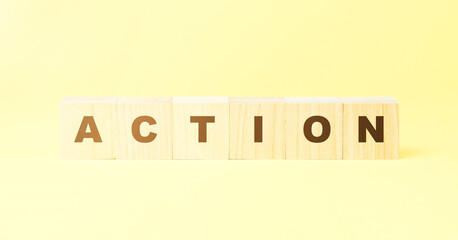 word action made with wooden cubes on yellow background