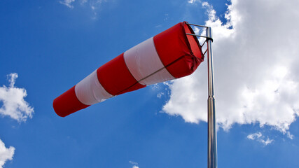 Windsock. Windsock flag. Wind direction indicator. Wind intensity. Windsock in front of blue sky.