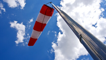 Windsock. Windsock flag. Wind direction indicator. Wind intensity. Windsock in front of blue sky.