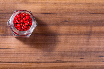 Closeup in glass jar with grains of red pepper on wooden background