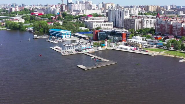 Top view of embankment with sailing yachts on background of city. Video. Beautiful panorama of large city near coast with yachts for sailing