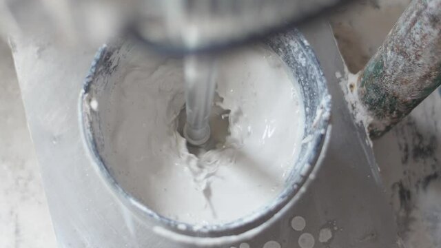 machine mixing gypsum in a bucket electric plaster whisk slow motion