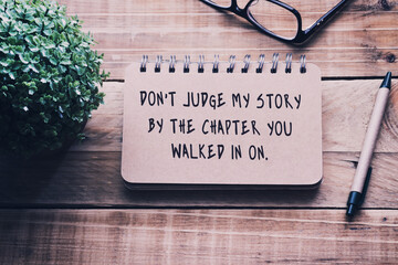 Inspirational and motivational quotes on a notepad - Don't judge my story by the chapter you walked in on . Blurry retro style background.
