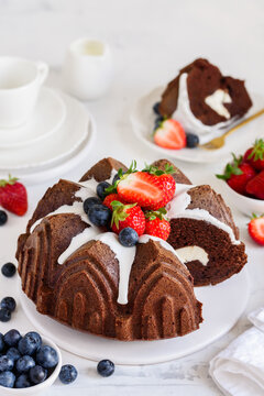 Chocolate bundt cake with cream cheese filling, decorated with fresh strawberries and blueberries. Selective focus.