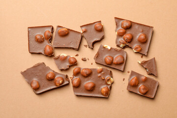 Chocolate pieces on beige background, top view. Sweet food