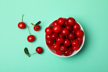 Bowl with fresh red cherry on mint background, top view