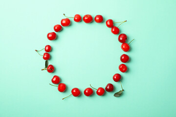 Circle made of red cherry on mint background, top view
