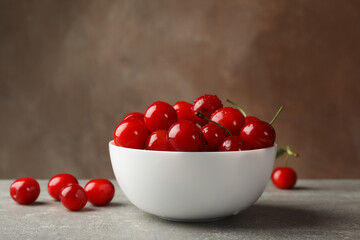 Bowl with red cherry on gray table, space for text