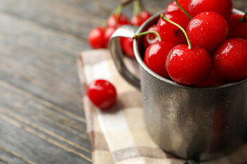 Towel and metal mug with cherry on wooden background. Summer plant