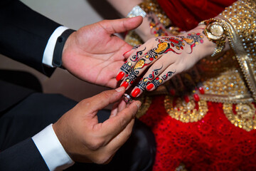 A groom puts the ring on the finger of bride. Indian Wedding.