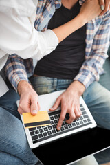Fototapeta na wymiar Top view of woman embracing boyfriend using credit card and laptop at home