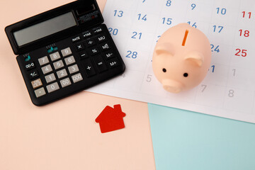 New house purchase, mortgage schedule reminder or real estate payment day, red house and piggy bank with calculator on white clean calendar.
