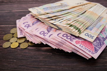 Ukrainian hryvnia and coins on a wooden background.