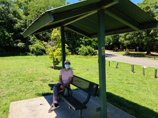 A person sits in the park seats with wearing face masks to prevention of infectious disease.