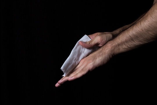 Men's hands are wiped with a wet towel on a black background. Hand hygiene. Hand disinfection