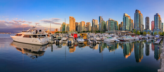 Sunset panorama at Coal Harbour in Vancouver British Columbia with downtown buildings boats and reflections in the water