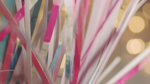 Close up of paper snippets rustling sound with defocused fairy lights in background. 4K resolution macro shot. Shallow depth of field. High quality audio recorded with condenser microphone.