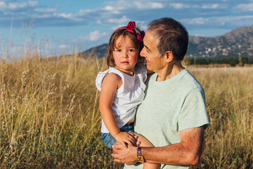 Fototapeta premium Grandfather with his granddaughter in arms at sunset at sunset