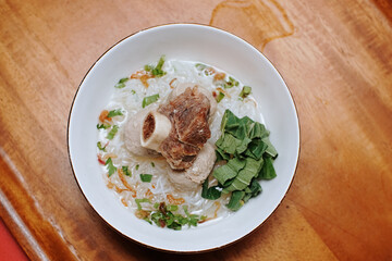 meatball soup with vermicelli and beef ribs. indonesian street food. white bowl. pieces of mustard leaf