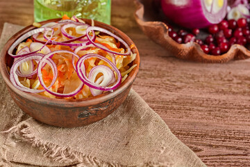 SauPickled cabbage in bowl with wooden spoon and seasoning on dark rustic kitchen table background.Fermented cabbage, german and russian style cuisine. Marinated vegetables. Vegetarian food.