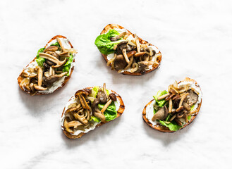 Mixed wild mushrooms cream cheese grilled bread sandwiches on a light background, top view