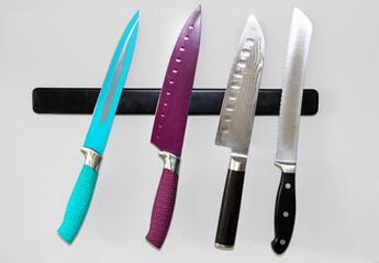 Kitchenware utensils- Set of four colorful knives placed on the magnetic block (holder) on the...