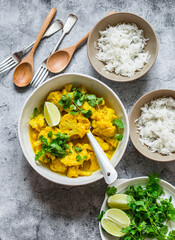Indian food lunch table - vegetarian cauliflower curry sauce, rice, cilantro, lime on grey background, top view
