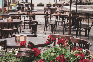 Empty outdoor cafe during quarantine, filtered. Restaurant terrace with tables and chairs, toned image. Street cafe with flowers. Elegant street cafe. Outdoor bistro furniture. Cozy patio background.