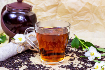 Fresh organic aromatic herbal tea in the glass cup with white jasmine flowers on light background.