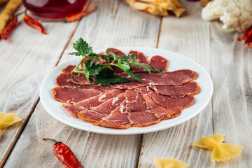 Sliced basturma slices herbs wooden background