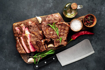 Two grilled beef steaks with spices on a stone background