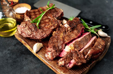 Two grilled beef steaks with spices on a stone background