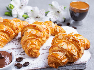 Yummy freshly three croissants sliced almonds with coffee and chocolate paste, close up