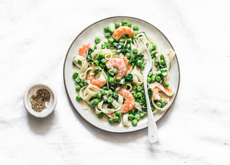 Green peas, shrimps, spinach, cream sauce tagliatelle pasta  on a light background, top view