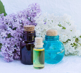 Glass bottles with essential oil, tincture, perfume and lilac flowers for Spa and aromatherapy. Selective focus
