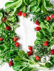 Fresh garden vegetables herbs and ripe strawberries on a light background with copy space, top view. Flat lay