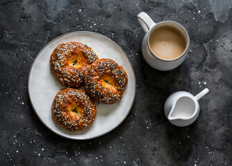 Savory cheese buns and coffee with cream on a dark background, top view. Delicious breakfast, brunch