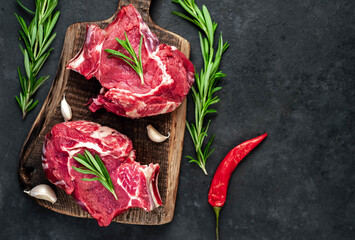 Two raw beef steaks with spices on a stone background 
with copy space for your text