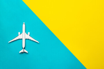 Kids playing toys. White airplane, aircraft in top view on bright blue and yellow backdrop. Flight air plane travel background with copy space for sky fly concept.