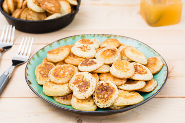 Trend breakfast. Dutch mini pancakes on plate and two forks on a wooden table. Close-up