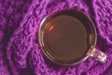 Obraz na płótnie Canvas cup of tea wrapped in a scarf as a concept of warmth and coziness top view