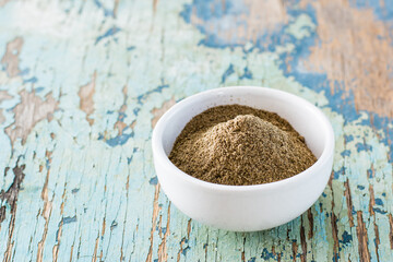 Black ground pepper in a white bowl on an old wooden table. Spice to improve the taste of cooked dishes. Copy space