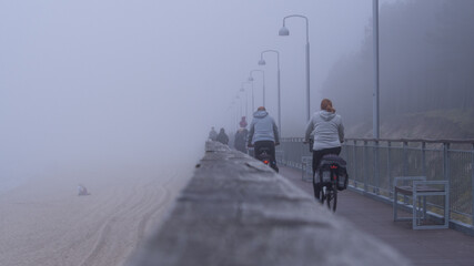 Rowerzyści na promenadzie w mglisty dzień - obrazy, fototapety, plakaty