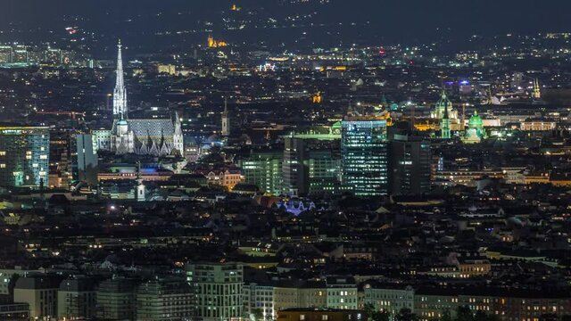 Aerial panoramic view over Vienna city with skyscrapers, historic buildings and Domkirche St. Stephan night timelapse in Austria. Illuminated skyline from Danube Tower viewpoint