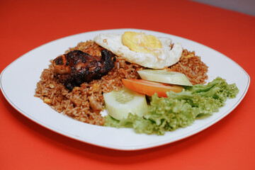 Indonesian fried rice with sunny side up and grilled spare ribs. fresh tomato lettuce and cucumber