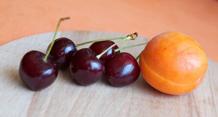 apricot and some cherries on a wooden tray