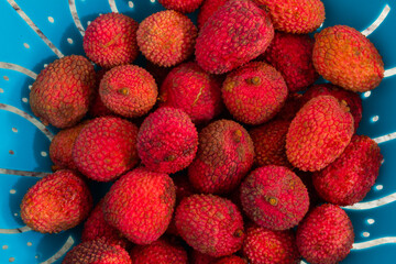 top view of many red lychees in a green basket