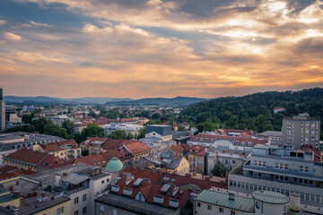 Fototapeta na wymiar Aerial view of Ljubljana city at sunset. Colorful golden hour over city buildings with hills in the distance. Capital city of Slovenia in summertime. Colorful clouds in the sky
